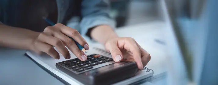 Person using a calculator and taking notes, possibly planning for a new business.