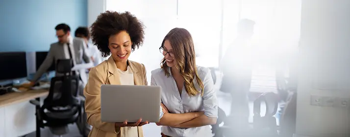 Two businesswomen in Dubai discussing a laptop, possibly starting a new business.