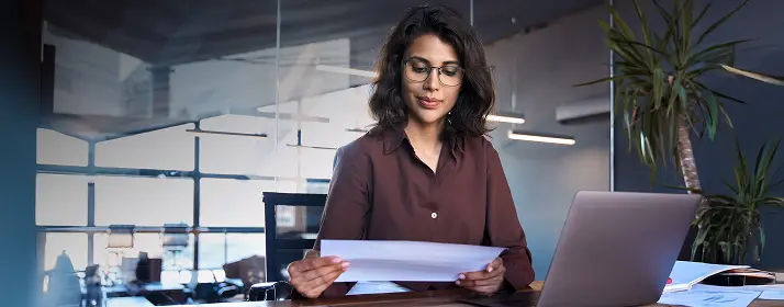 Businesswoman reviewing documents in her office, possibly planning to get start your business in dubai.